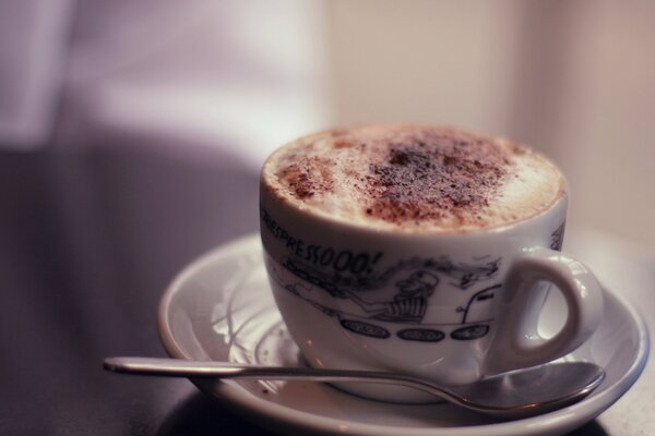 Cappuccino with foam in a white cup on a blurry background