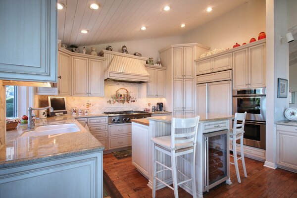 Cuisine moderne en bois avec des chaises sur de hautes jambes dans un décor blanc