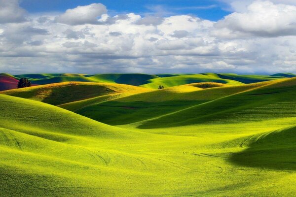 Meadow with hills and daytime sky with clouds