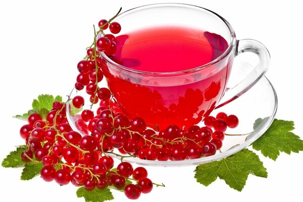 Red drink in a transparent mug with currant berries on a saucer