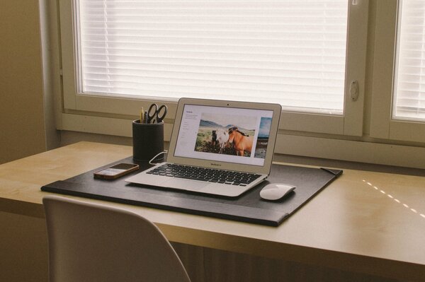 A MacBook with a mouse on the table