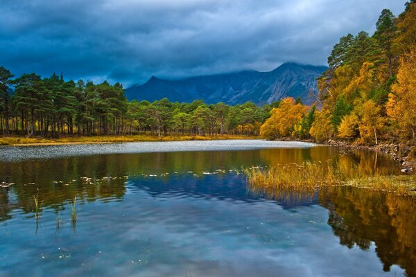 Autumn lake with forest and mountains in the background