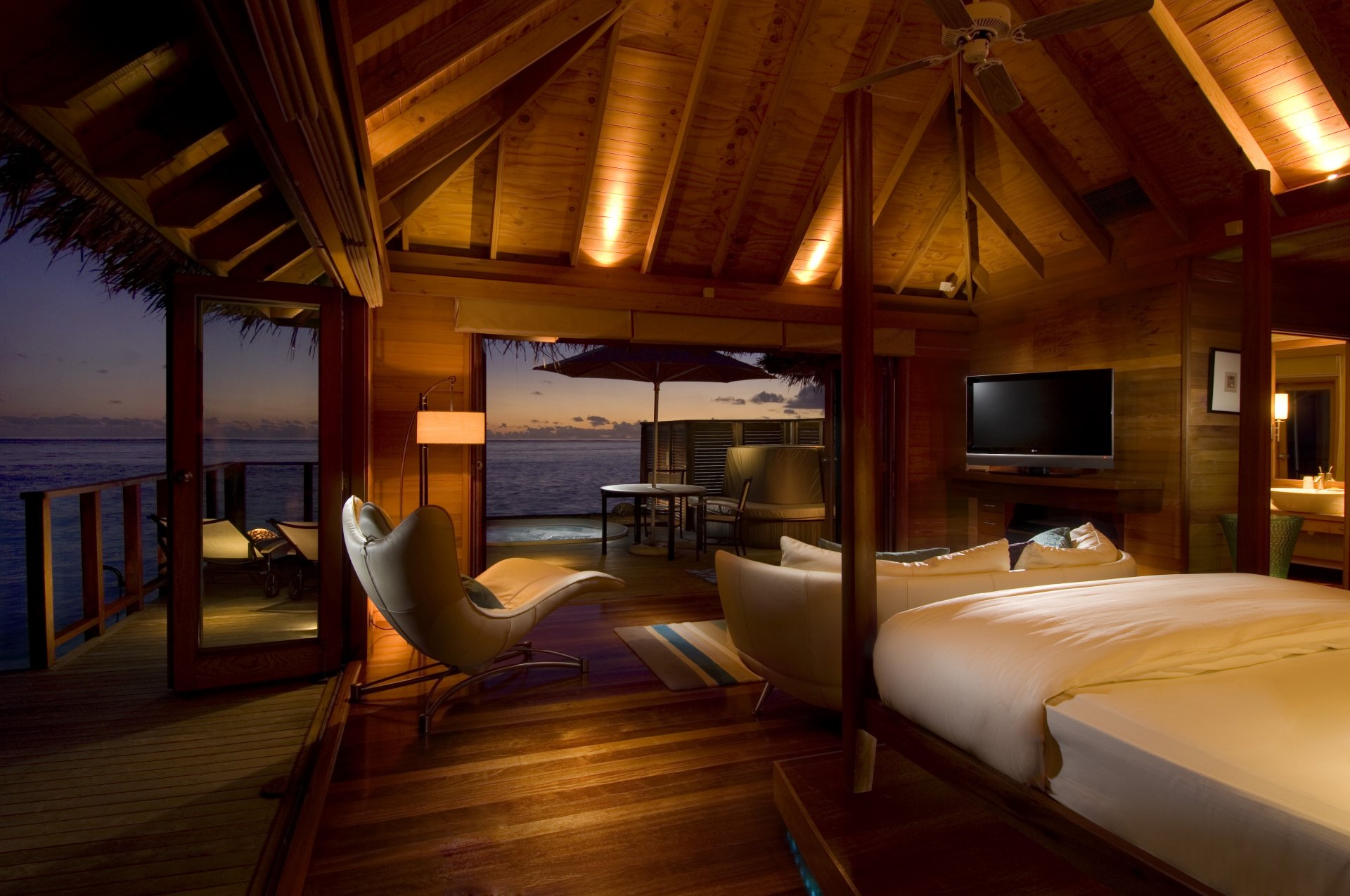 interior bungalow dormitorio cama sofá sillón tv tumbonas jacuzzi iluminación mar