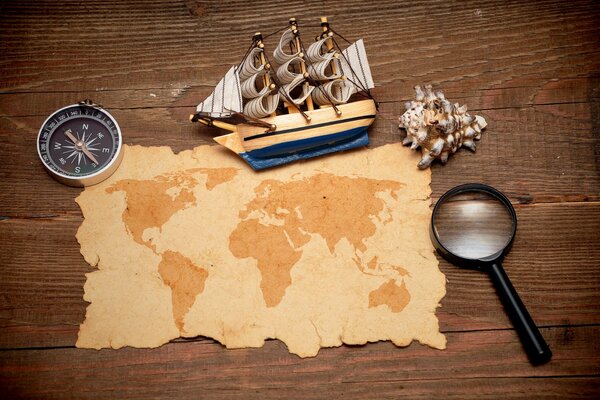 World map with compass, magnifying glass and ship