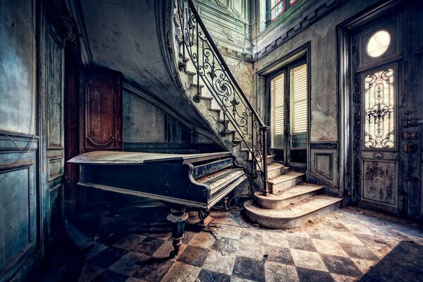 An old piano under the stairs in an old house