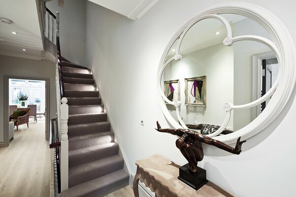 Интерьер дома с крутой лестницей и зеркалом
