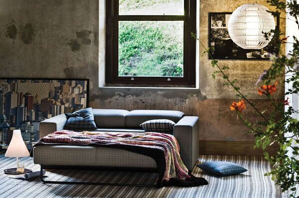 Sofa with a blanket and pillows by the window