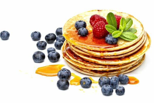 A pile of pancakes with honey and berries