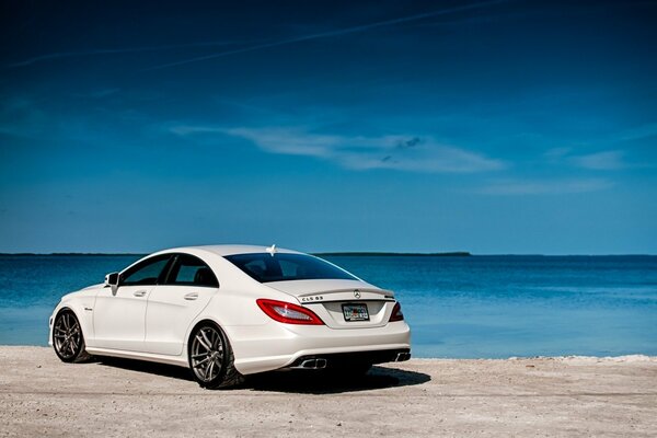 Mercedes blanco contra el mar y la arena