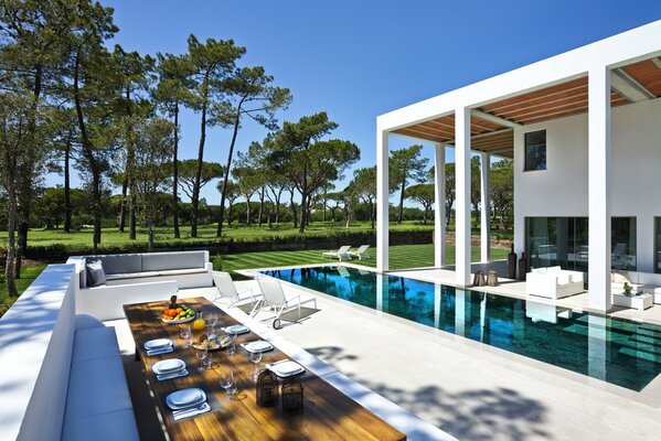 Hermoso interior de la casa con piscina transparente. Alrededor de la piscina sofás, tumbonas