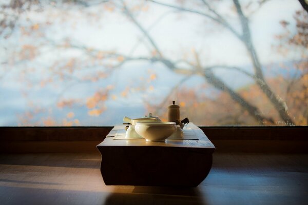 Table with cups on the background of the autumn view outside the window