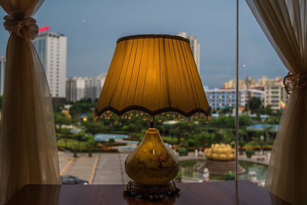 Lampe sur la table près de la fenêtre avec une belle vue sur la ville