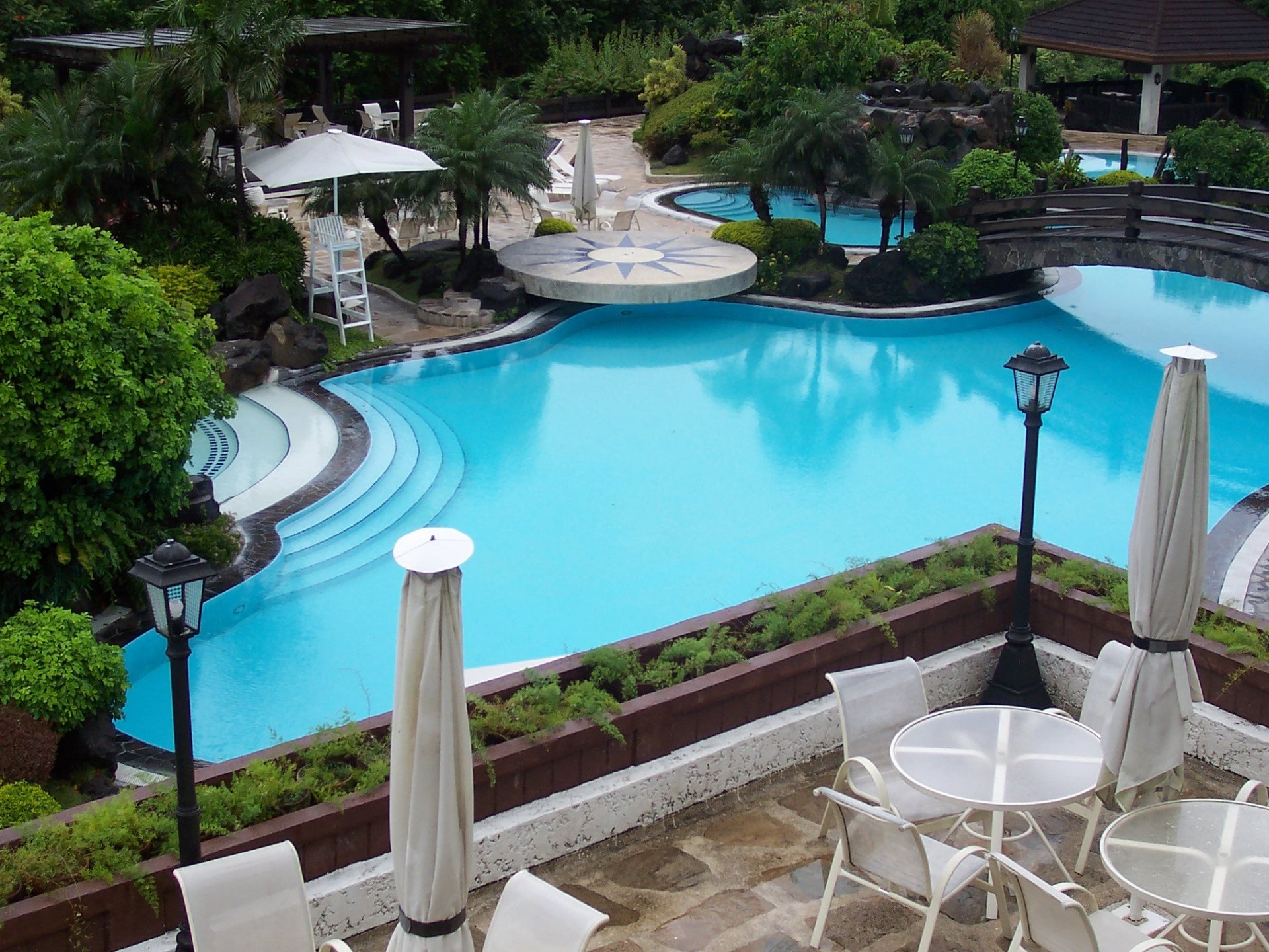 piscine pont pierres tables chaises arbres lanternes