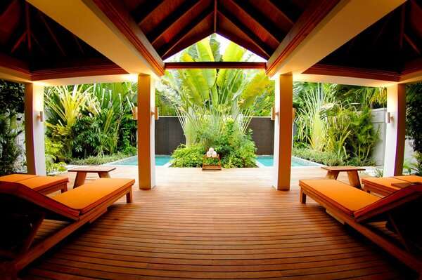 Intérieur près de la piscine: chaises longues et tables sur fond de verdure tropicale