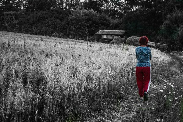 Eine Frau geht die Straße zwischen einem Weizenfeld entlang