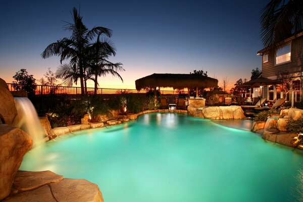 House with swimming pool palm trees and waterfall