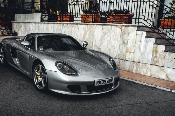 A silver Porsche stands at the top of the steps