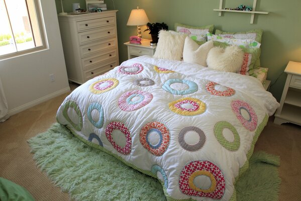 Letto in camera da letto con cuscini e coperta colorata