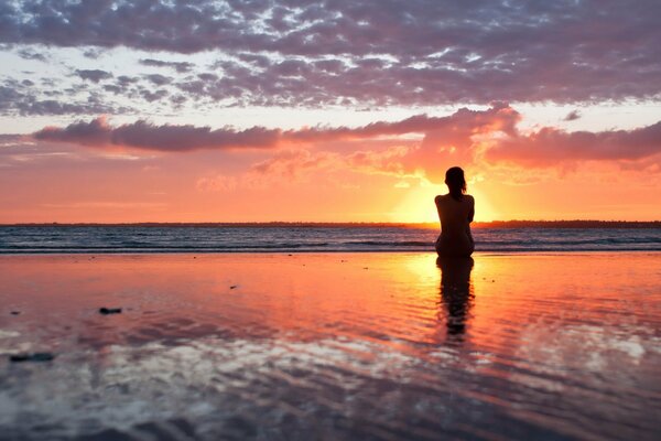 Fille sur la rive en regardant le soleil couchant