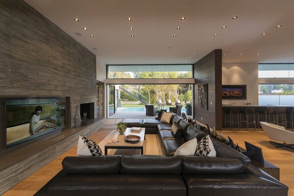 Enorme sala de estar de estilo moderno con sofás de cuero y acceso a la piscina