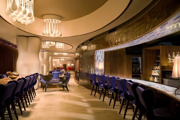Интерьер роскошного ресторана с длинной барной стойкой и футуристическими светильниками