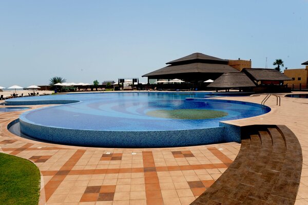 Piscine ronde avec bar, plage et shizlongs