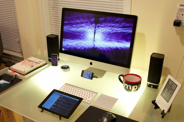 Sobre la mesa hay un libro, un Teléfono, un gadget y un Monitor
