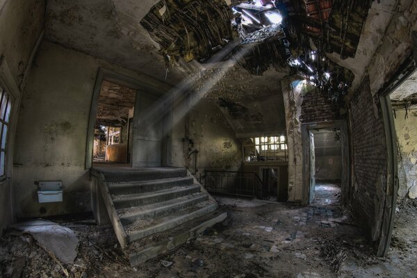 An abandoned, ruined building with steps, the sun s rays peeping through the broken roof