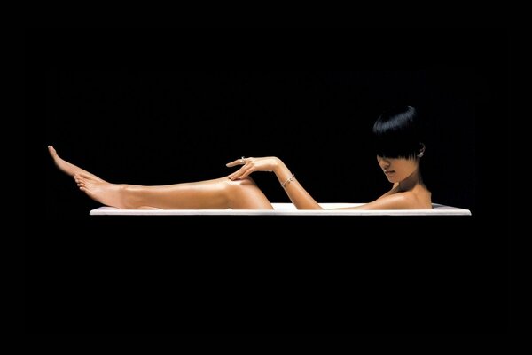 The girl is lying in the bathroom on a black background