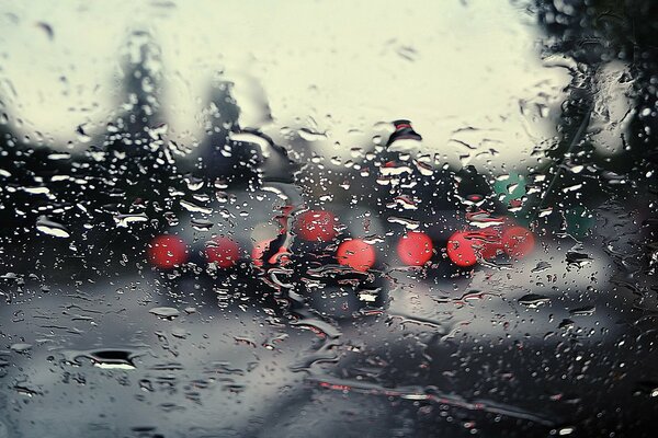 Tropfen nach dem Regen auf Glas vor dem Hintergrund des Scheinwerferlichts