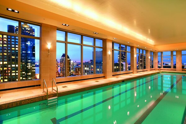 The surface of the water of an empty pool and the view of the city from its windows