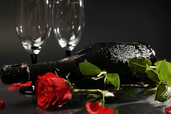 A misted bottle of champagne with a rose and a romantic dinner