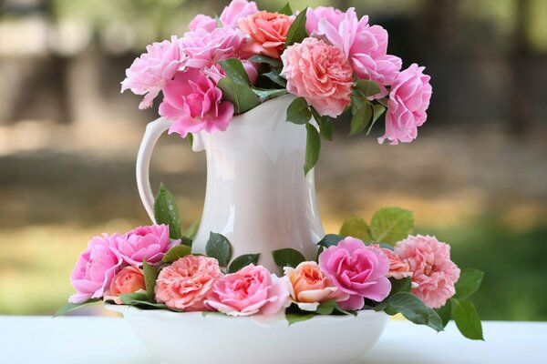 A pitcher with pink flowers on a plate