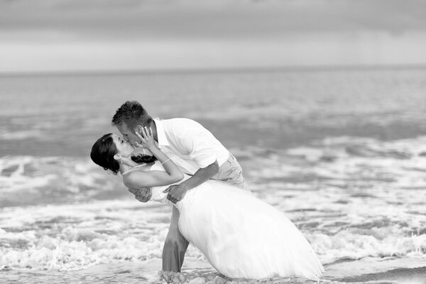 Мужчина и женщина на свадьбу целуются на берегу