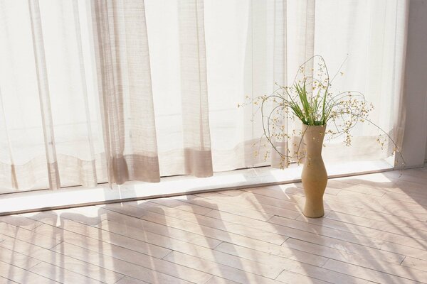 Chambre lumineuse avec rideaux et vase blanc