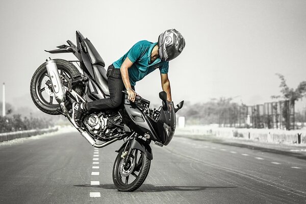 Un motocycliste fait une cascade dangereuse sur une moto noire au milieu de la route