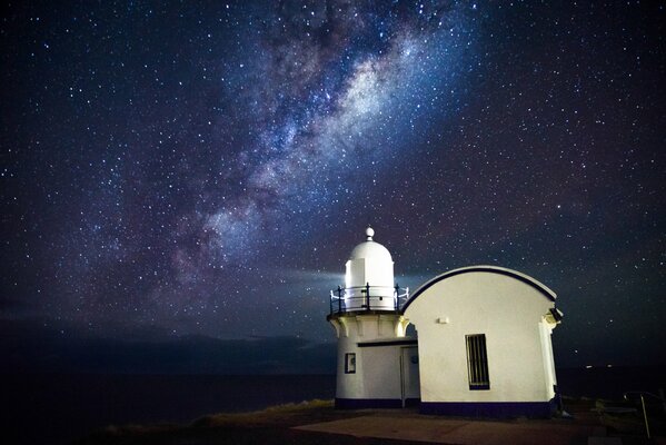 Lighthouse standing by the sea and clear starry sky