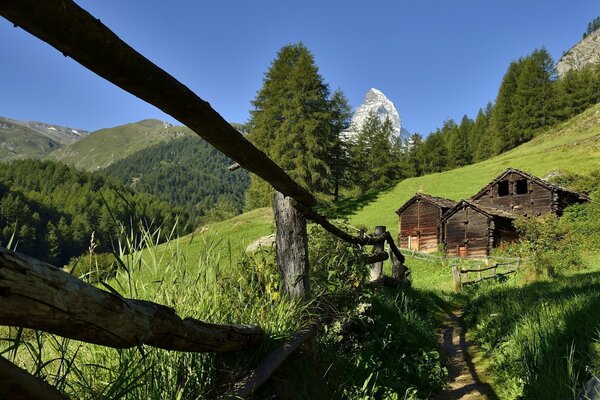 In den Bergen hinter einem Zaun ein Holzhaus