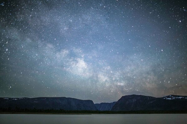 Lac de nuit illuminant la côte avec un ciel étoilé