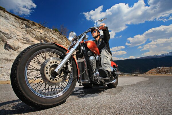 A biker on a motorcycle slowed down by the road