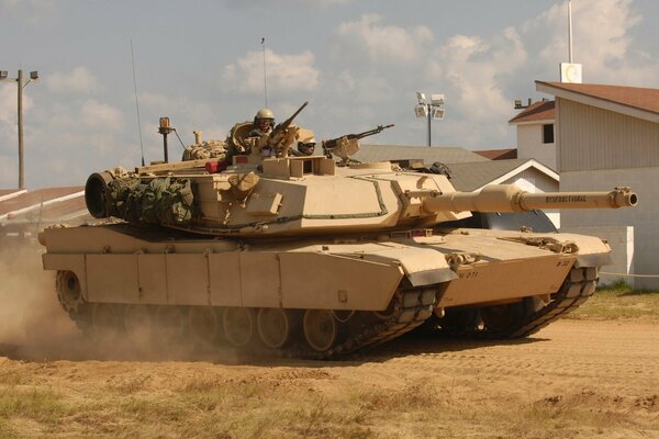 Amerikanische gepanzerte Fahrzeuge der Abrams-Panzer mit einem Tanker auf einem Turm in einer sandigen Landschaft