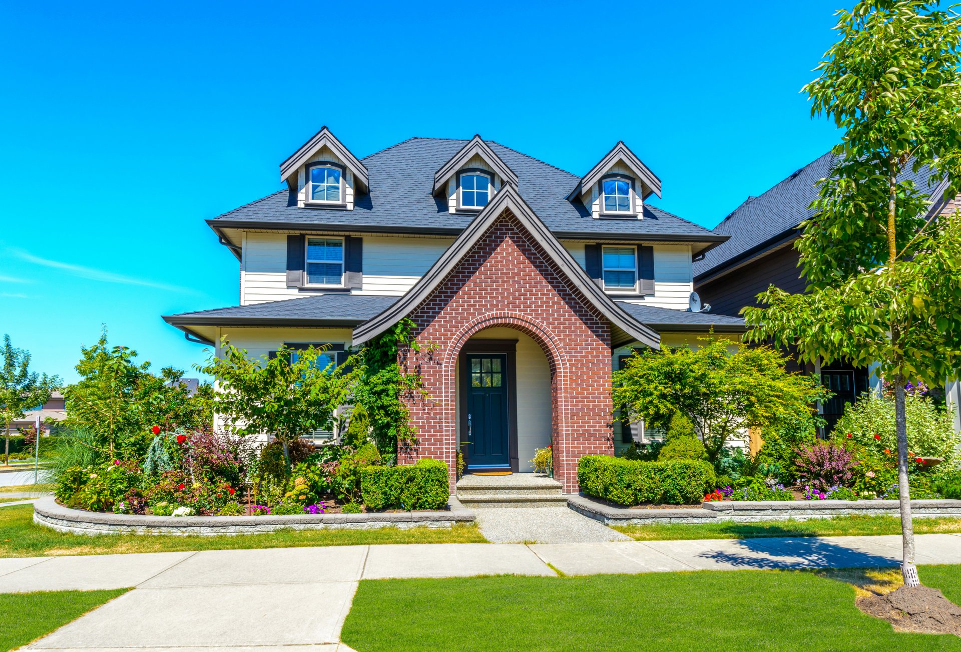 house mansion design lawn bushes flowers greenery grass sidewalk sun sky blue