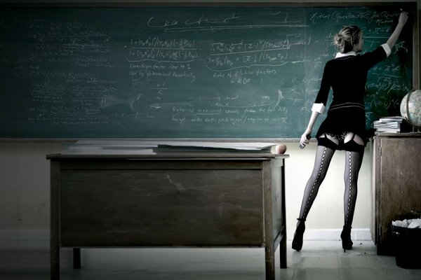 Lehrerin in schwarzen Strümpfen schreibt an die Tafel