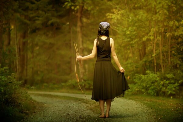 Ragazza con arco e frecce nella foresta