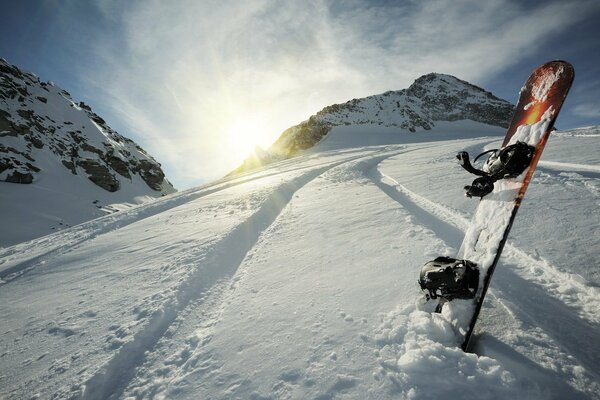 Bord en la nieve en medio de la montaña y el sol