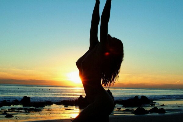 Silhouette de la mer de la jeune fille au coucher du soleil