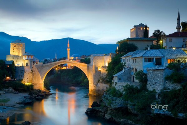 Ein abendliches Minarett, das von der untergehenden Sonne beleuchtet wird. Eine Brücke. Bosnien