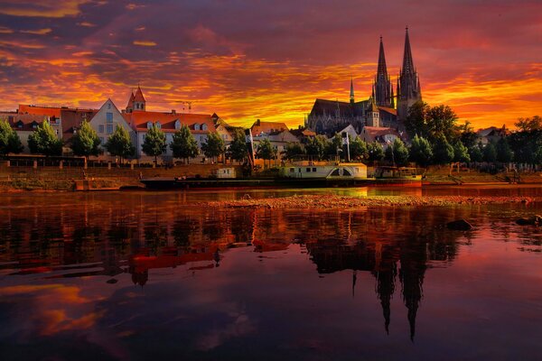 Sunset and burning sky in Regensburg, Germany. Reflection of the city and cathedral in the river