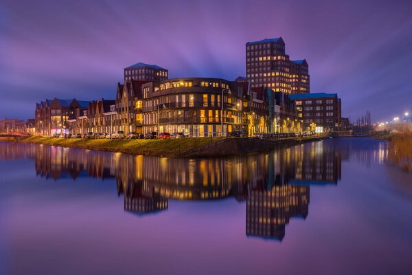 The glowing night city is reflected in the river