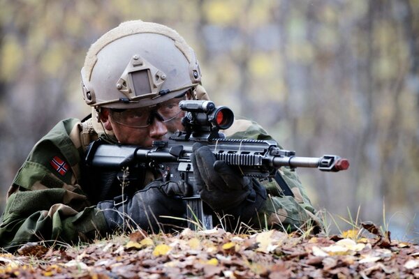 A soldier with a gun lies in ambush